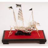 Two Chinese white metal junk boats, 20th Century, in glass cases and on wooden plinths,