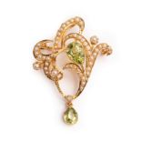 An Art Nouveau peridot and seed pearl pendant/brooch, of scrolling openwork form,