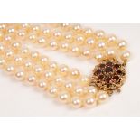 A three-row cultured pearl choker necklace, with garnet cluster clasp set in 9ct gold,