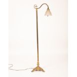 A brass standard lamp with clear flared glass shade on three claw feet,