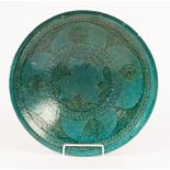 A Persian turquoise glazed ceramic plate with incised decoration,