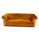 A Chesterfield sofa upholstered in dark ochre velvet, on castors,
