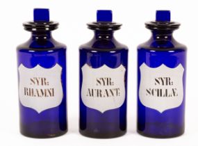 Three blue glass apothecary drug jars and stoppers with inscribed overlay shield-shaped white