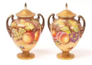 A pair of Royal Worcester two-handled vases and covers painted by Leaman, with peaches, apples,
