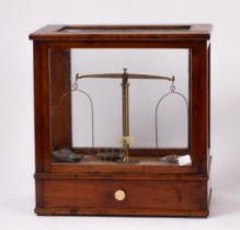 A pharmacists scale by Oertling, London in a glazed case, the drawer with various weights, 34.