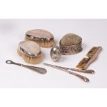 A pair of silver mounted oval brushes, Birmingham 1835, a Victorian silver mounted hat pin cushion,