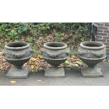 Three circular moulded garden vases on pedestal bases,