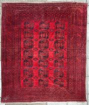 An Afghan carpet, the sang du boeuf field of three rows of seven octagonal quartered guls,