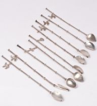 Nine sterling silver iced tea spoons/straws, 20th Century, seven hung with small charms, 21.