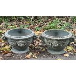 A pair of circular garden vases, moulded cherub mask heads and scrolls on circular squat bases,
