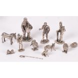 A group of white metal figures, including shepherd, chimney sweep, organ grinder, owl, donkey, etc.