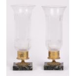 A pair of glass and marble candleholders, the flared cylindrical shades engraved with foliate swags,