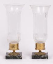 A pair of glass and marble candleholders, the flared cylindrical shades engraved with foliate swags,