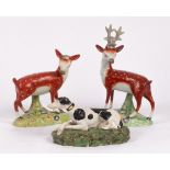 A pearlware figure of a recumbent hound with black patches, and a pair of a standing stag and doe ,