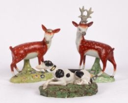 A pearlware figure of a recumbent hound with black patches, and a pair of a standing stag and doe ,