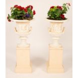 A pair of cast iron urns on plinths, painted, 87cm high x 39.