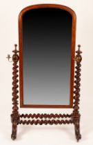 A mahogany cheval mirror, 19th Century, with candle sconces, on turned supports on scroll feet,
