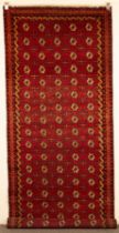 A Bokhara khelleh or long rug, Turkestan, strawberry red field of cruciform guls,