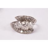 A diamond crossover ring, centred by three cushion-shaped old cut and round brilliant cut diamonds,