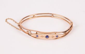 An Edwardian 9ct gold hinged bangle, set with three sapphires and diamond chips, approximately 6.