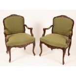 A pair of carved walnut armchairs with upholstered seat and padded backs,