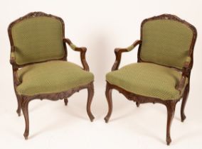 A pair of carved walnut armchairs with upholstered seat and padded backs,