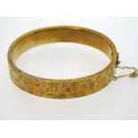 A 9ct gold bangle with chased decor, internal meas