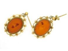 A pair of yellow metal drop earrings set with ambe