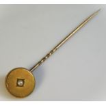 A yellow metal tie pin, head set with pearl, head