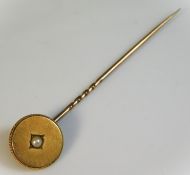 A yellow metal tie pin, head set with pearl, head