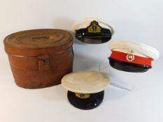 A steel hat tin twinned with three military caps,