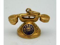 A gold telephone with enamelled dial charm, tests electronically as 18ct, 2.39g