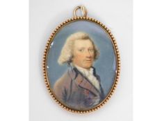 An 18thC. miniature portrait of a gentleman in purple coat & white cravat, set in 9ct rose gold case