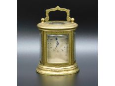 A 19thC. French oval miniature carriage clock with engraved decor, stamped to rear R A 122 & to the