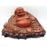 A c.1900 Chinese lacquerware laughing Buddha on carved hardwood organic plinth, marked "China" to un