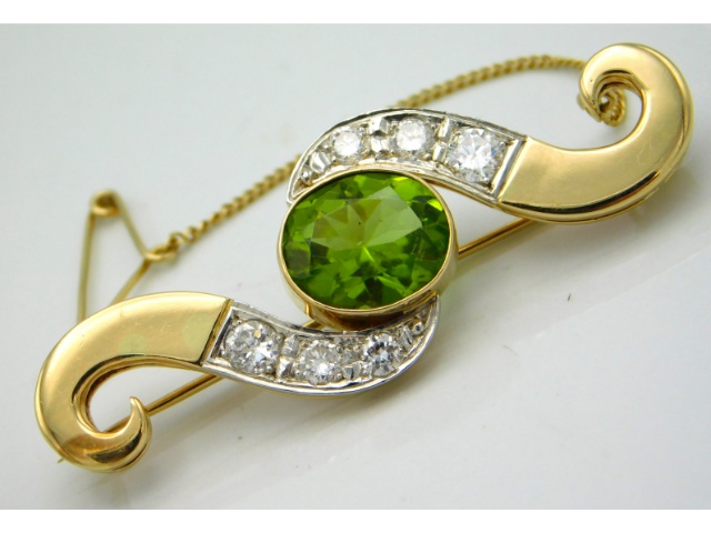 A gold brooch, tests electronically as 18ct, set with approx. 0.64ct diamond & a central peridot, 43