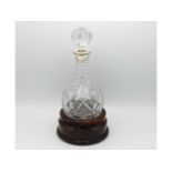 A silver topped cut glass decanter with hardwood s