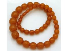 An amber necklace, largest bead 22mm, 25in long, 8