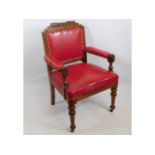 A carved oak desk chair with red leather style uph