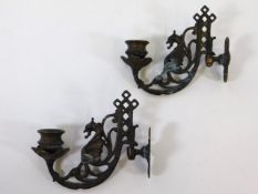 A pair of ornate brass wall sconces depicting drag