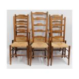 A set of six 20thC. rush seated oak ladder back chairs including one carver, 44.5 high to back