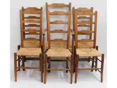 A set of six 20thC. rush seated oak ladder back chairs including one carver, 44.5 high to back