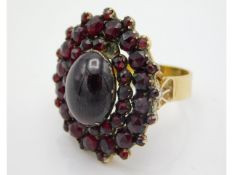 A yellow metal garnet cluster ring with central ca