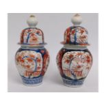 A pair of Japanese Arita style lidded vases, chip