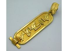 A yellow metal pendant with Egyptian hieroglyphics