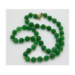 A vintage jade necklace with yellow metal fittings