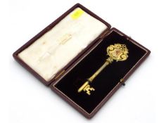 A cased silver gilt key with decorative enamelled