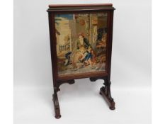 A large 19thC. mahogany framed needlepoint fire screen, 38.25in high x 23in wide