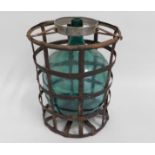 A green glass demi-john in caged mount, 21.5in hig