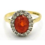 An 18ct gold ring set with fire opal & diamonds, main stone 9mm x 6mm, scratches to opal & chip, 3.6